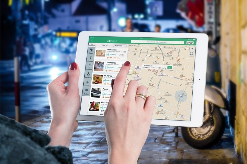 woman holding an iPad pointing to a map on the screen