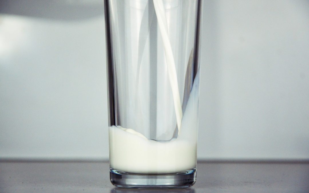 milk being poured into a glass cup