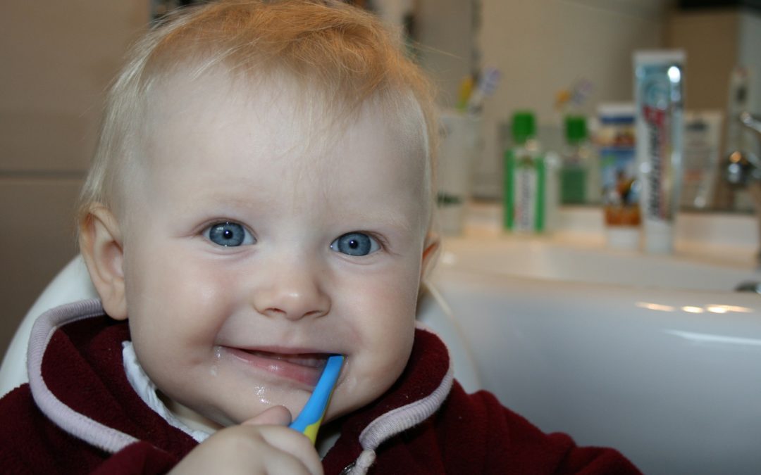 toddler smiling while brushing his teeth